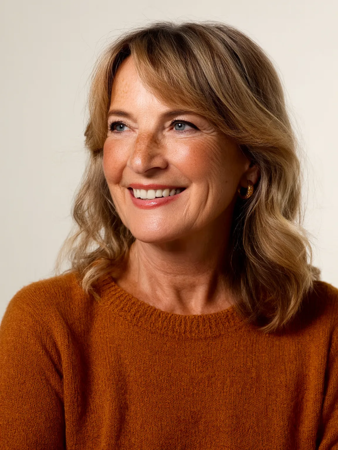 Soft Warm Ash Blonde Wavy Layers with Side-Swept Bangs